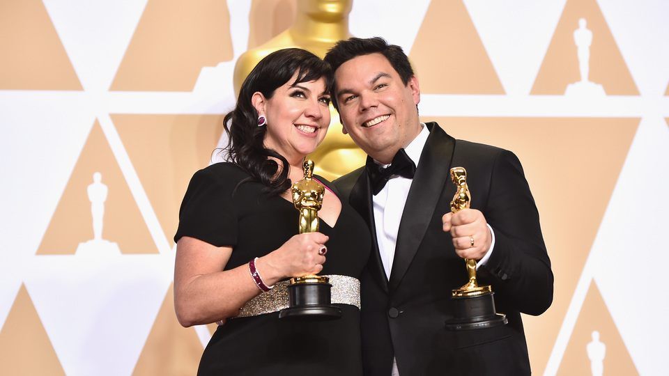 Composers Kristen Anderson-Lopez (L) and Robert Lopez, winners of the Best Original Song award for 'Remember Me' from 'Coco,' pose in the press room during the 90th Annual Academy Awards at Hollywood & Highland Center on March 4, 2018 in Hollywood, California. (Photo by Alberto E. Rodriguez/Getty Images)
